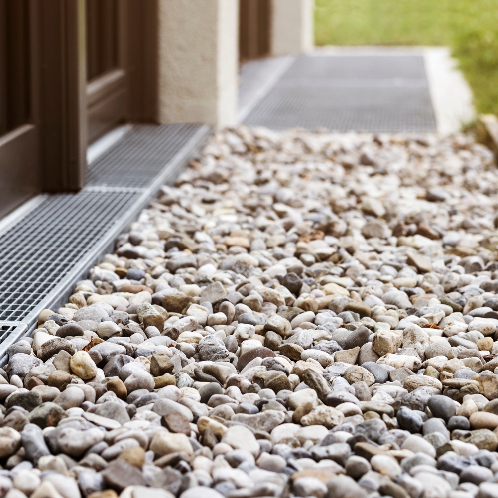 French drain with water Stones near House Wall