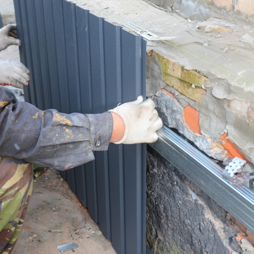 Old house foundation wall repair and renovate with installing metal sheets for waterproofing and protect from rain. Foundation repair